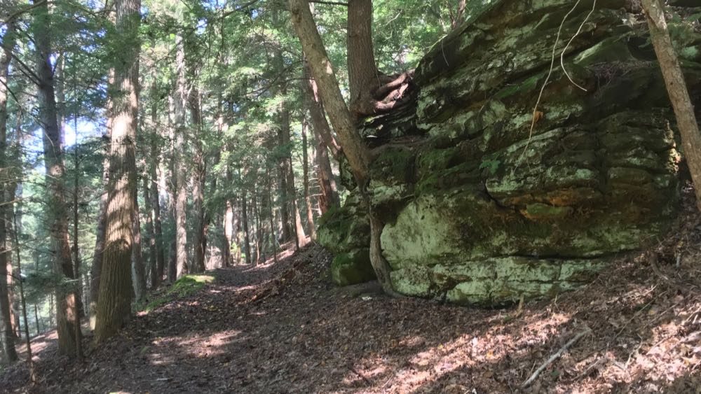 A trail at Clear Creek Metro Park that is passing a large rock formation.